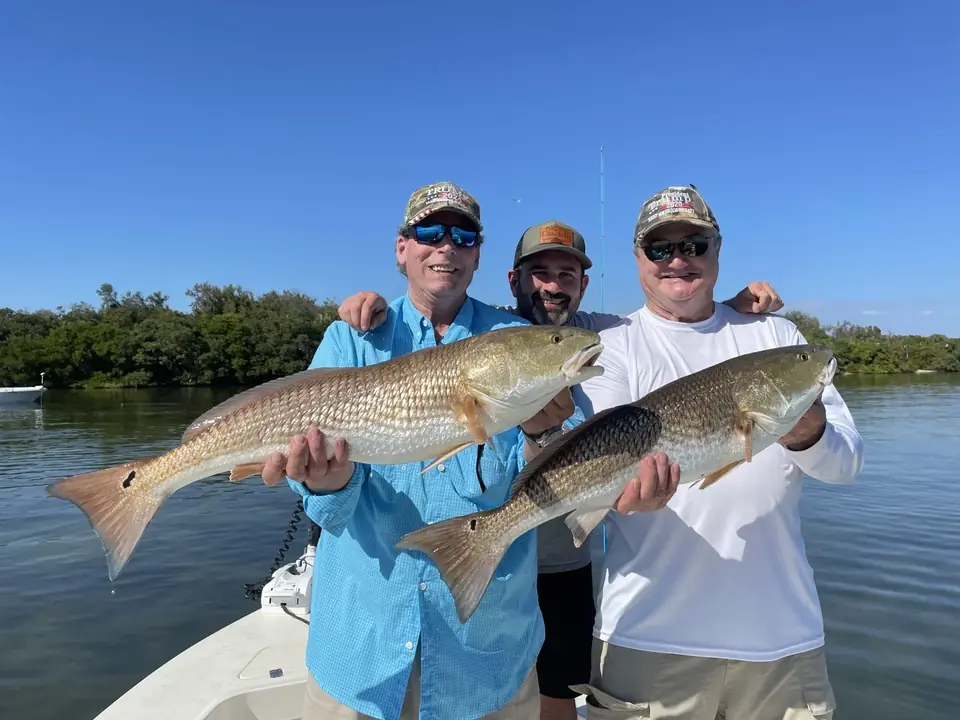 Two anglers on a Big Daddy Sportfishing charter holding a pair of redfish