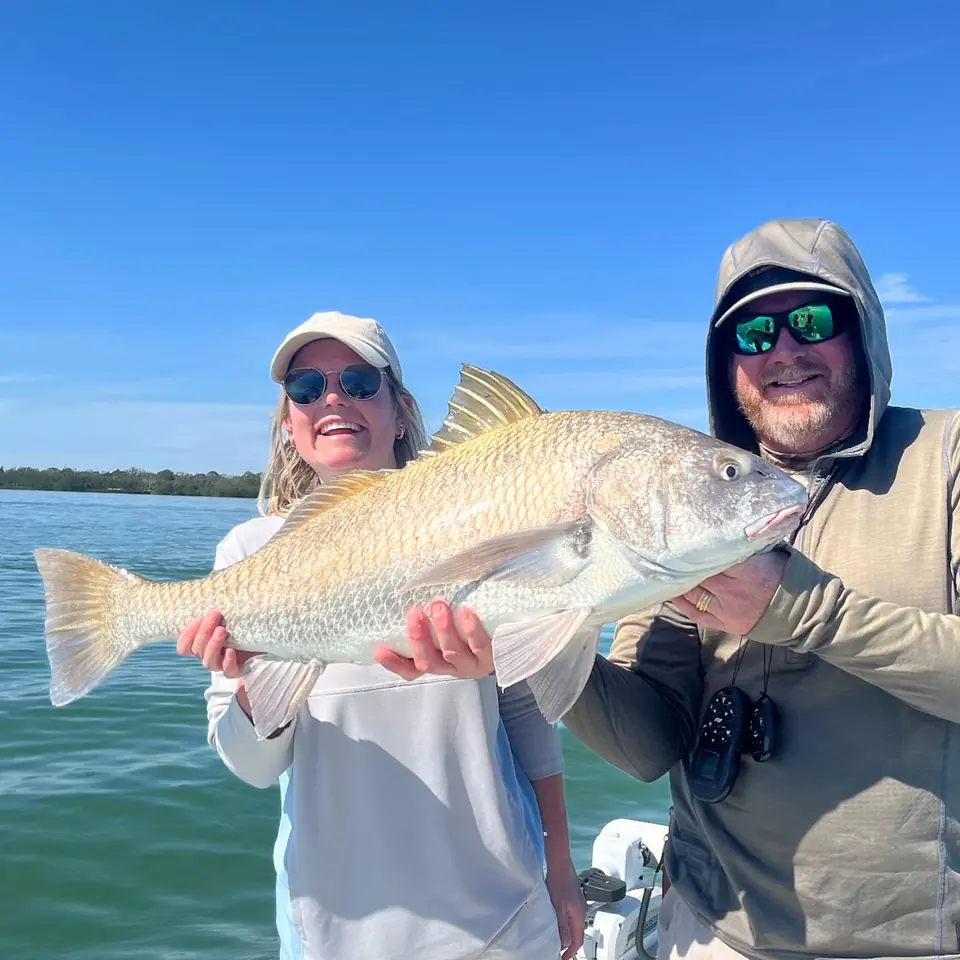 Couple holding a redfish caught on a Tampa Bay fishing charter