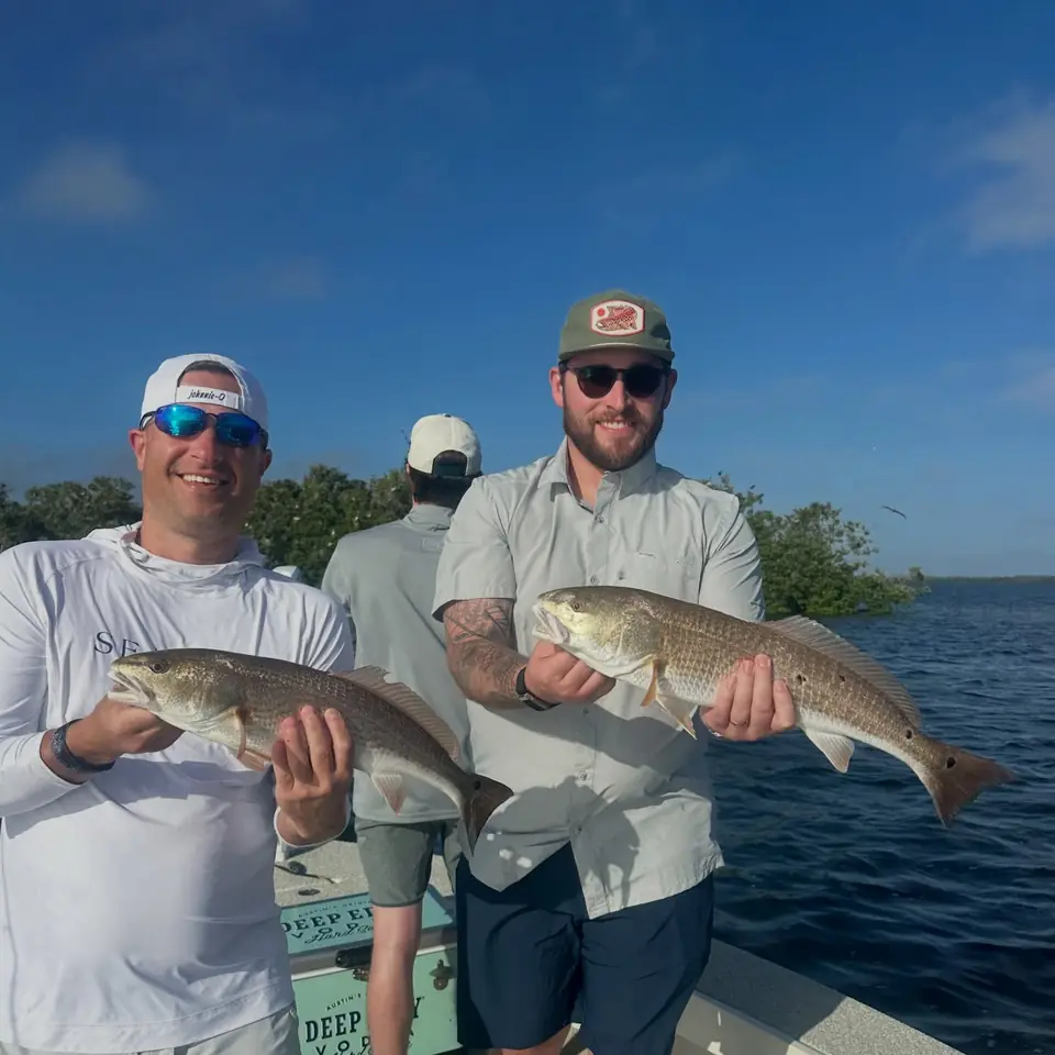 Two anglers holding a pair of redfish caught inshore in Tampa Bay with Big Daddy Sportfishing.