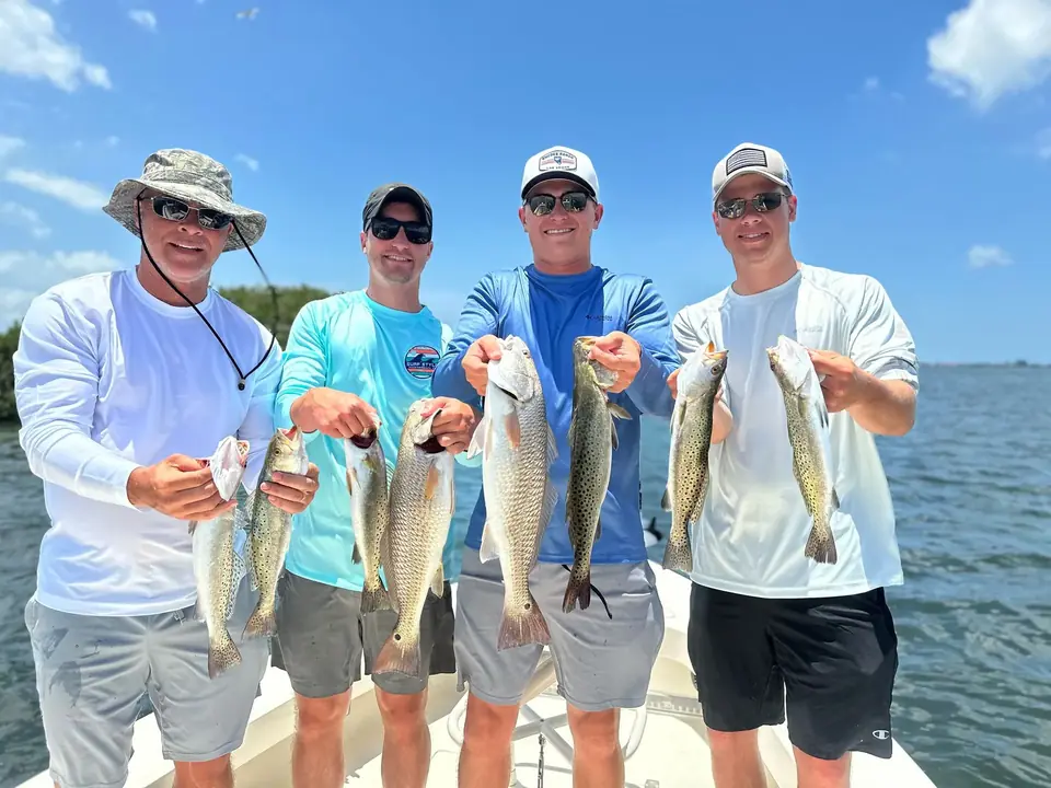 Four anglers holding their catch on a Tampa Bay inshore fishing charter