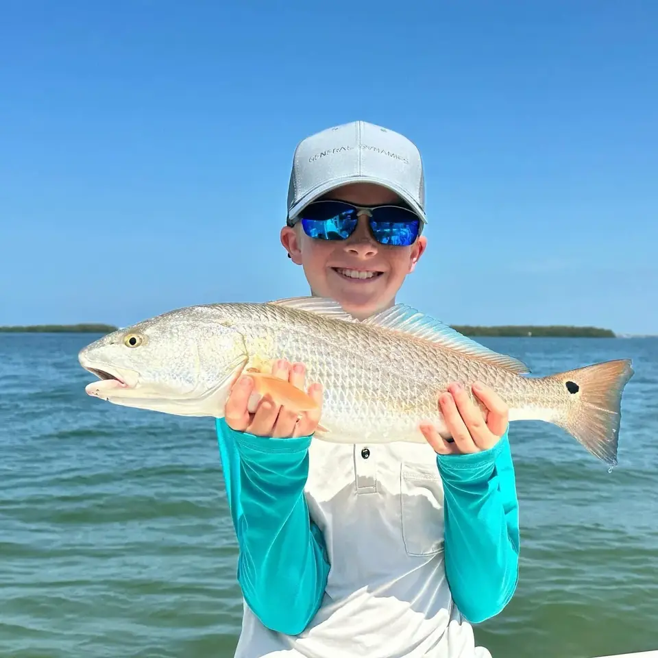 Young angler holding a redfish caught on a Tampa Bay fishing charter with Big Daddy Sportfishing